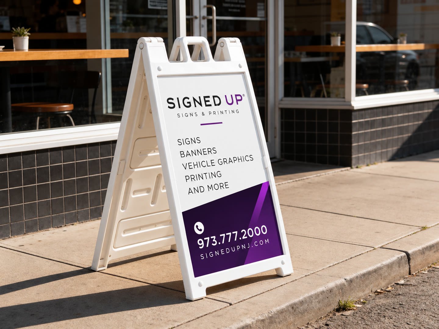 White plastic A-frame sidewalk sign with a Signed Up insert outside a storefront
