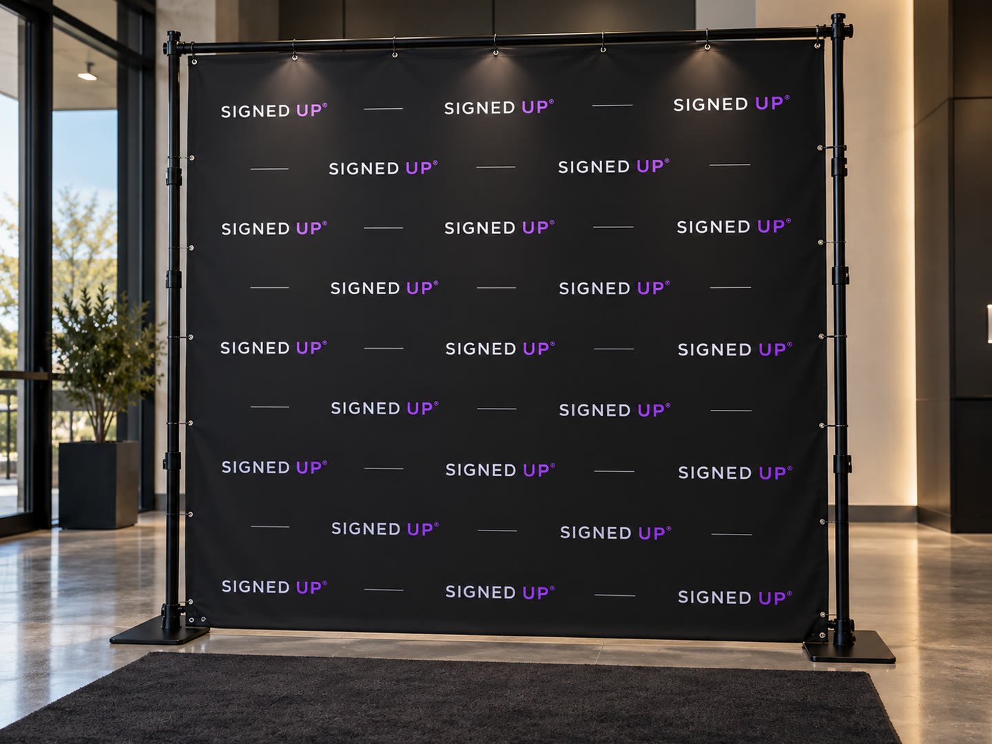 Black Signed Up step and repeat backdrop hung on a telescopic stand in a lobby