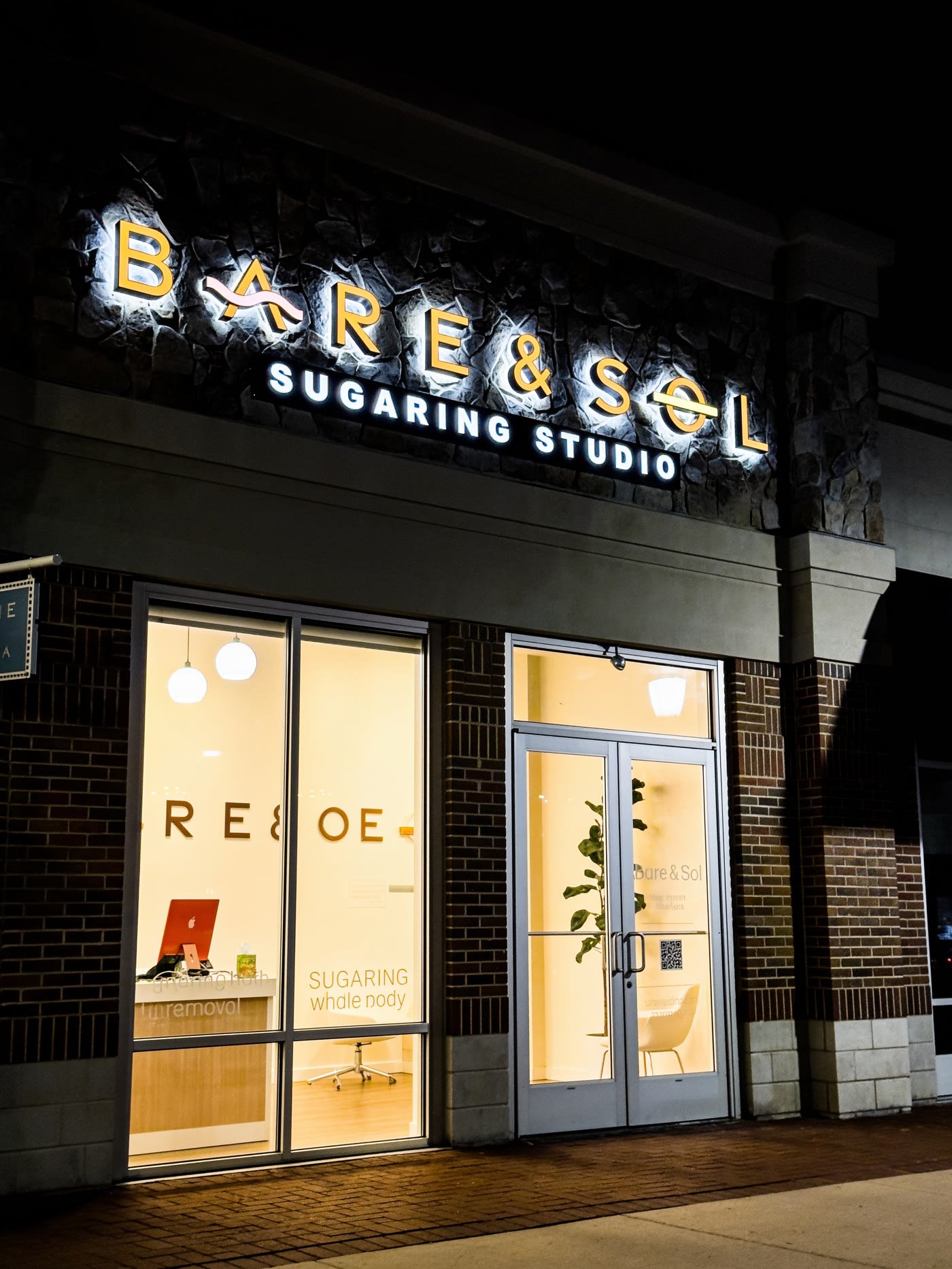 Halo-lit letters on a stone storefront at night